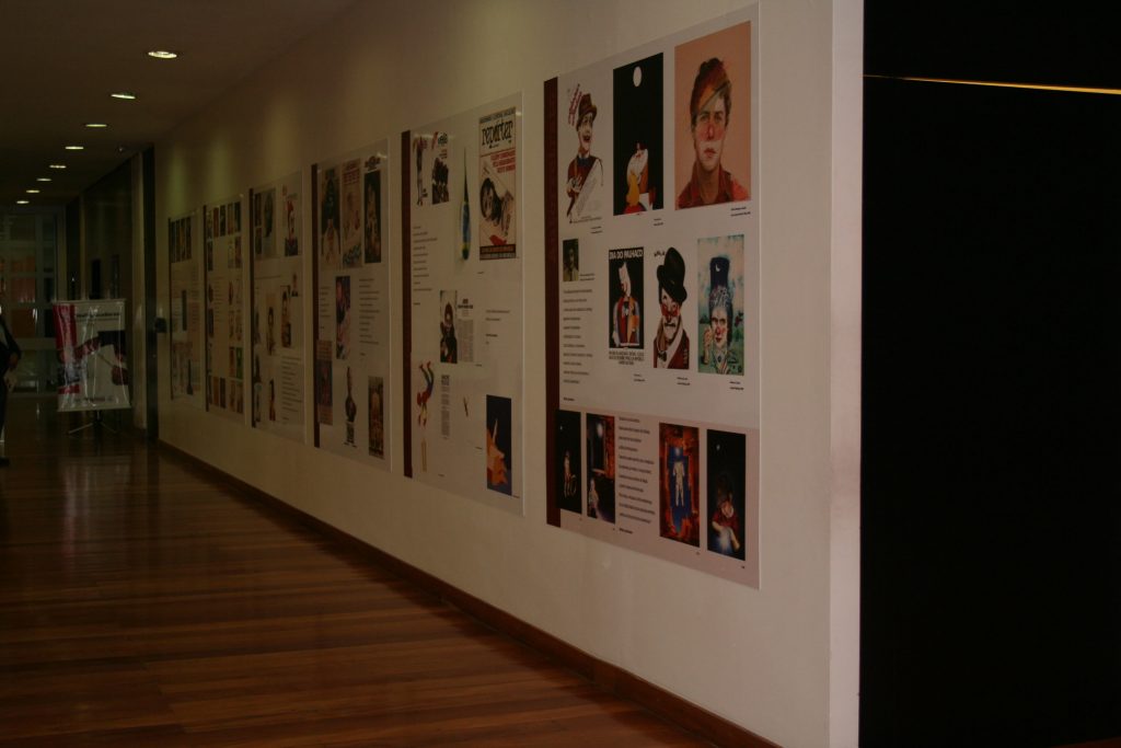 Foto colorida de parede branca com vários cartazes coloridos expostos e alguns escritos. Neles podemos ver figuras humanas.
